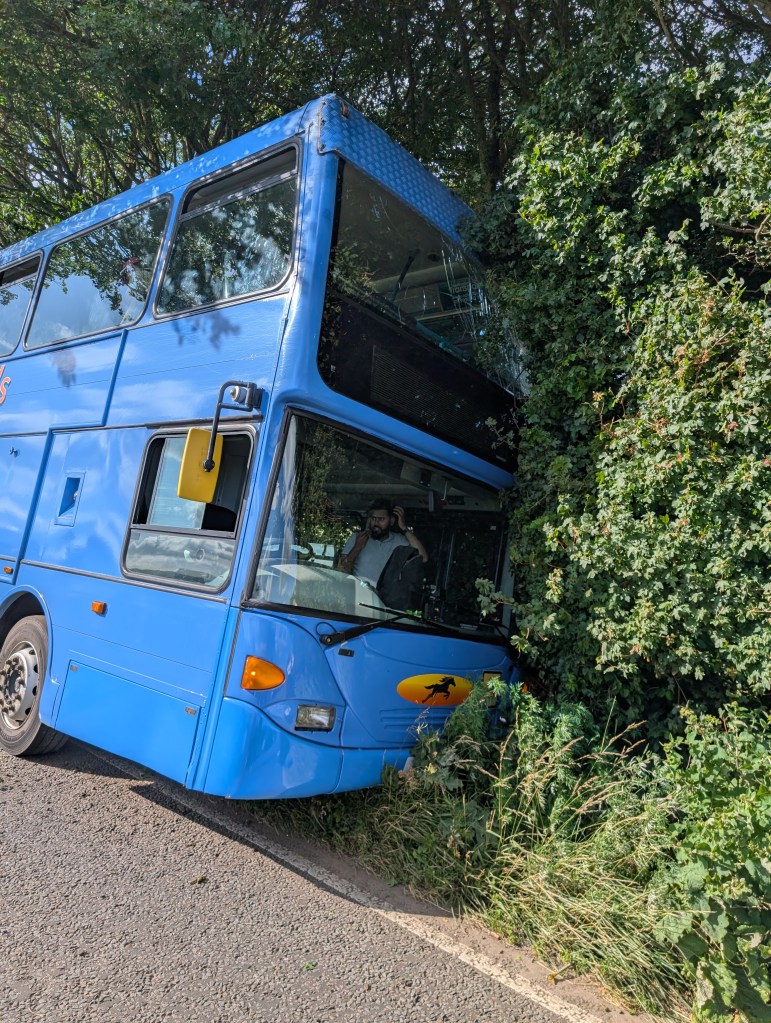 Silverstone F1 shuttle bus crash site. The bus is inches from fully tipping over, only saved by trees.
